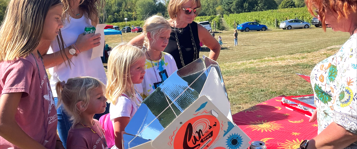 A family viewing a solar oven demonstration