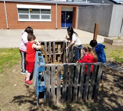 Elementary students tending to the school compost bin.